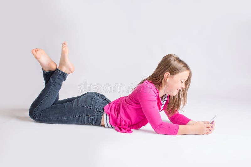 Young girl lying on belly laughing while using her cell phone. Young girl lying on belly laughing while using her cell phone