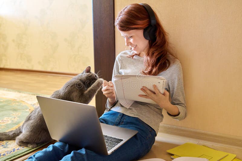 Preadolescente estudiando en casa usando laptop junto con gato fotografía de archivo