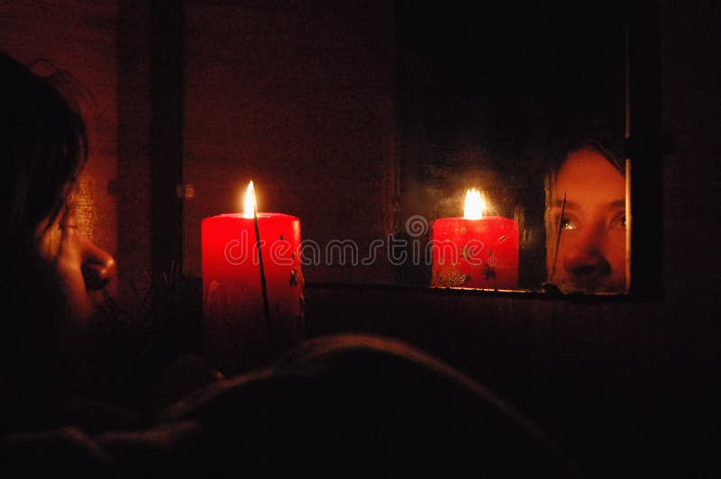 Predizione di Natale Una ragazza esamina la sua riflessione in uno specchio da lume di candela immagine stock Predizione di Natale Una ragazza esamina la sua riflessione in uno specchio da lume di candela immagine stock
