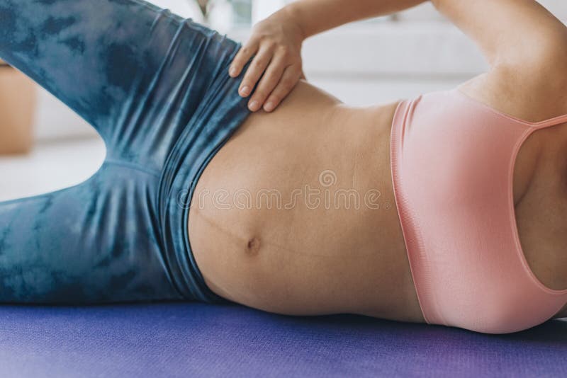 Pregancy pilates side lying clam exercise for pelvic stability and hip muscles training. Pregnant woman working out on