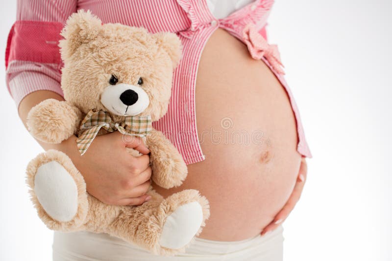 Pregnancy. Pregnant woman holding teddy bear toy in his hand, st