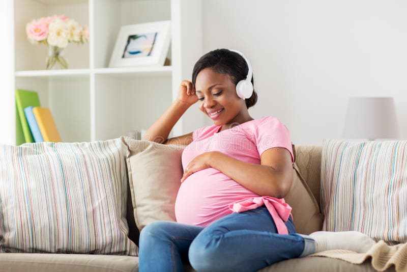 Premium Photo  Happy pregnant woman holding headphones on her belly at  home pregnancy people technology concept