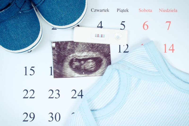 Pregnancy test, ultrasound scan of baby and clothing for newborn on calendar with polish words, expecting for baby stock photos