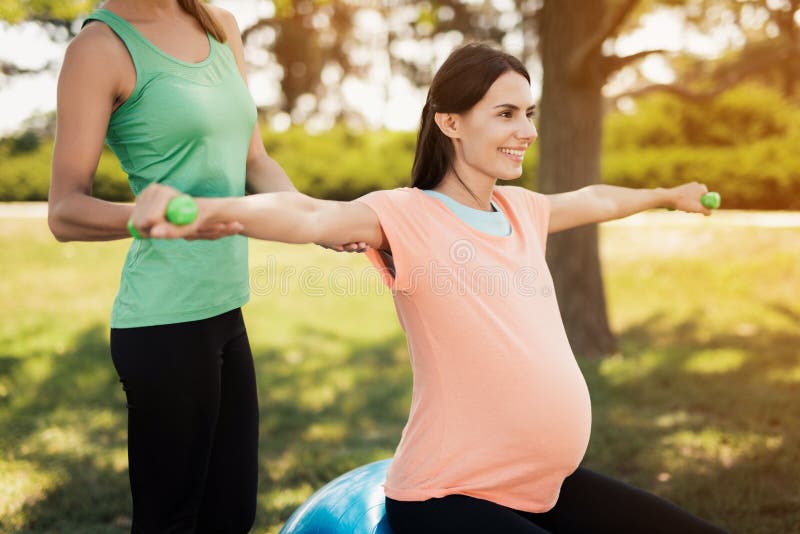 Pregnancy Yoga. a Coach Helps a Pregnant Woman To Do Exercises on