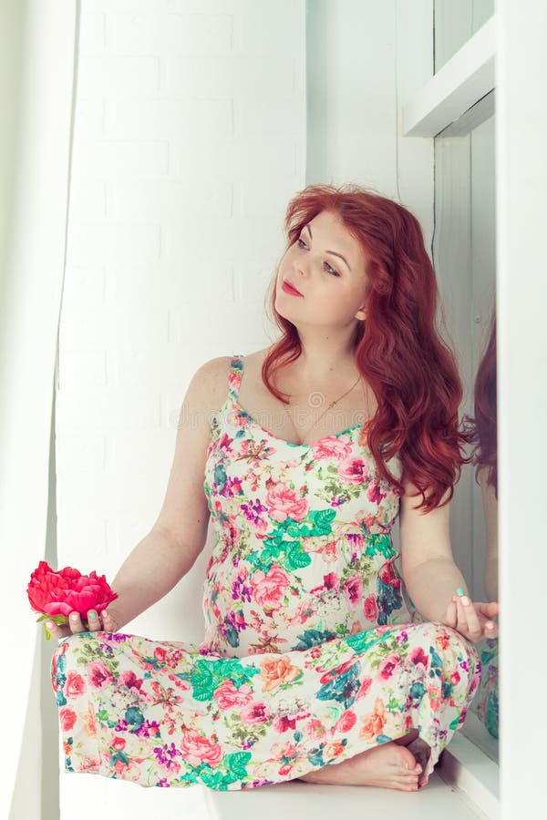 Pregnant Beautiful Red-haired Woman Sitting On A Window 