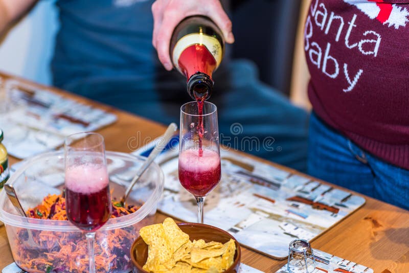 Pregnant female in christmas pullover holding bottle and pouring red non alcoholic wine into champagne glass on table royalty free stock photo Pregnant female in christmas pullover holding bottle and pouring red non alcoholic wine into champagne glass on table royalty free stock photo