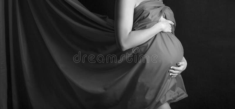 Pregnant girl belly. Artistic studio shot on black backgroound