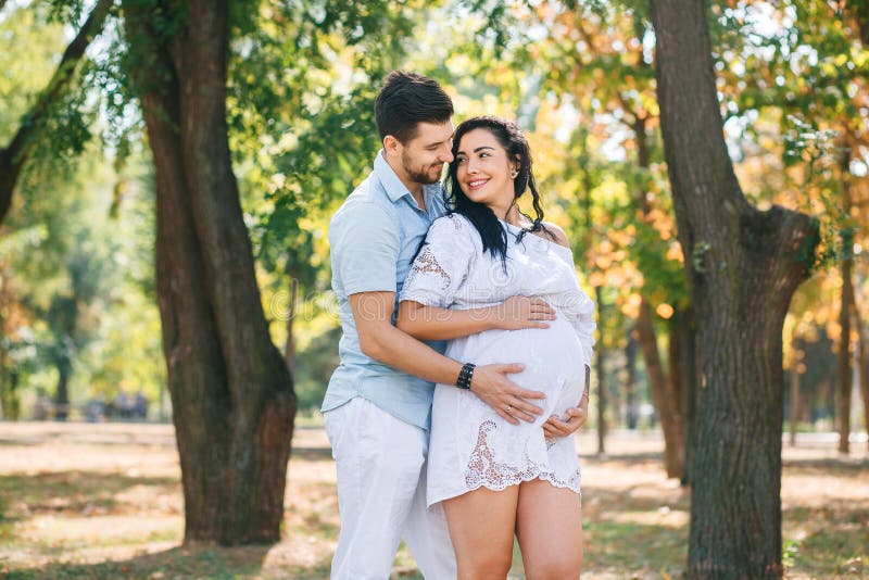 Pregnant Girl Walks In The Park With Her Husband Hugging And Kissing Enjoying The Beautiful 