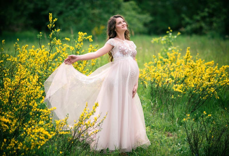 Pregnant Happy Woman in a Beautiful Dress in a Blooming Yellow Field ...