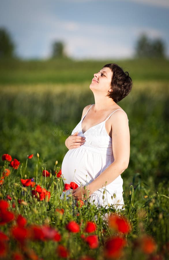 Pregnant happy woman in a flowering poppy field