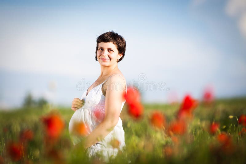 Pregnant happy woman in a flowering poppy field