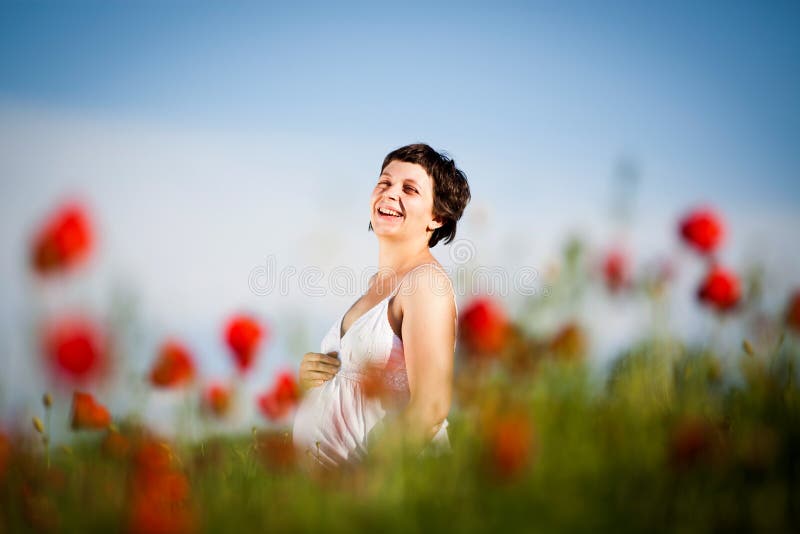 Pregnant happy woman in a flowering poppy field