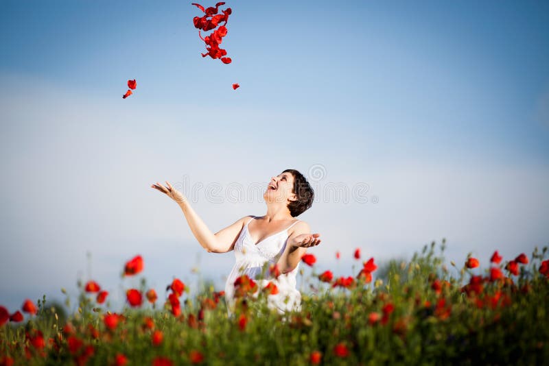 Pregnant happy woman in a flowering poppy field