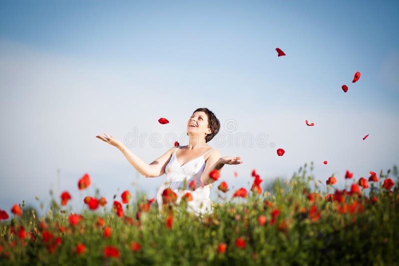 Pregnant happy woman in a flowering poppy field