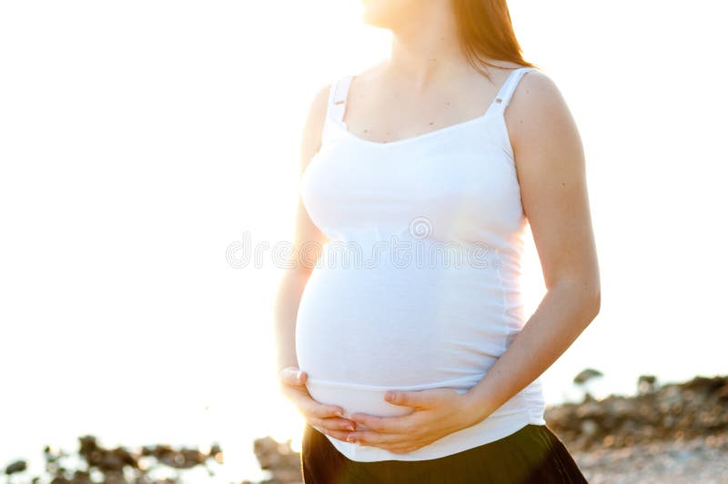 Schwangere Frau in Natur hält Ihren Bauch.