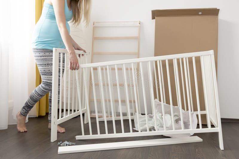 Pregnant woman assembling bed for expectant baby