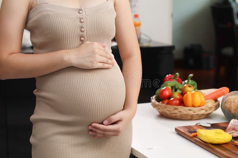 Pregnant woman in dress holds hands on belly on a white background. Pregnancy, maternity, preparation and expectation concept. stock image Pregnant woman in dress holds hands on belly on a white background. Pregnancy, maternity, preparation and expectation concept. stock image