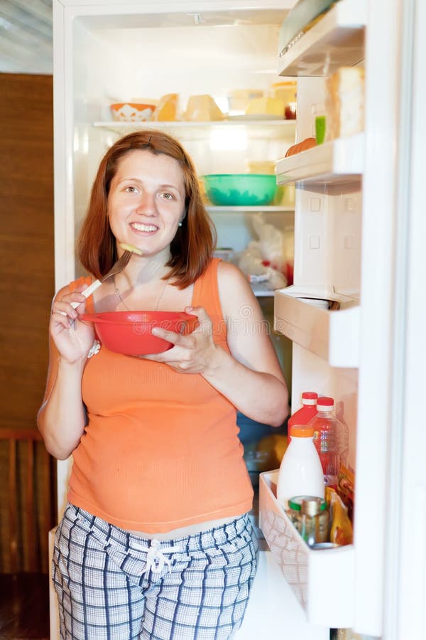 Pregnant woman eats from refrigerato stock image Pregnant woman eats from refrigerato stock image