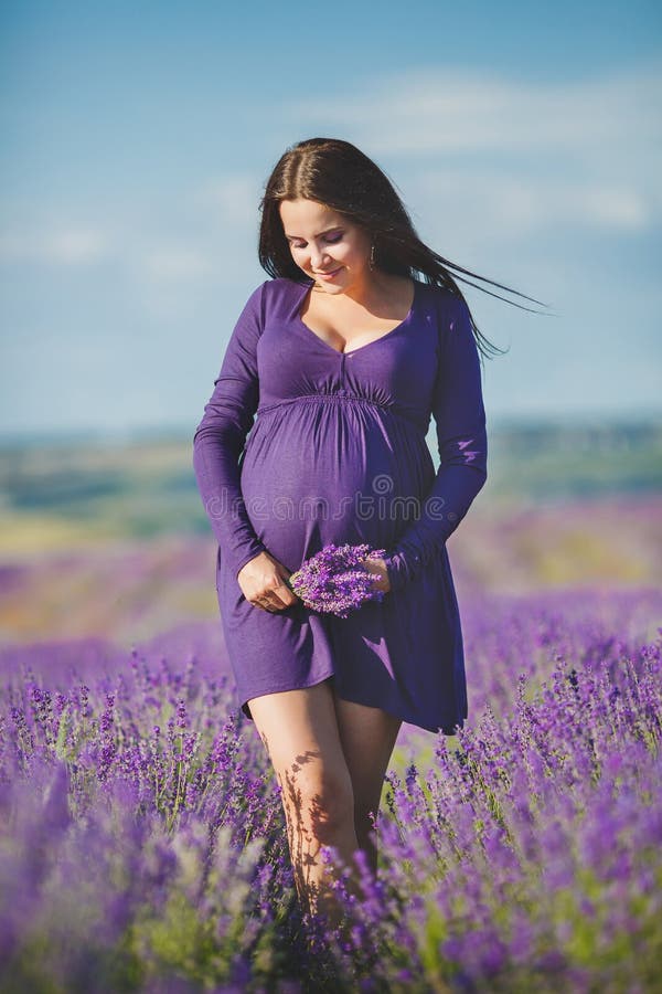 Langhaarige hübsche schwangere Frau in einem Lavendel-Feld mit Korb der Lavendel Blumen.