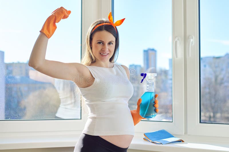 Pregnant Woman In Gloves Looking At Camera Near Clean Washed Window