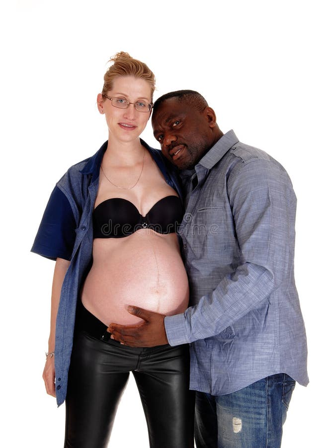 An African American men and his Caucasian pregnant wife standing isolated f...