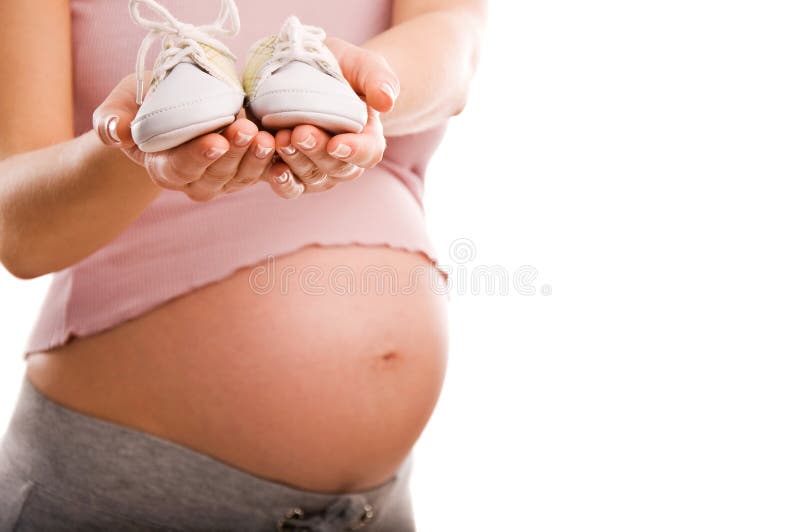 Pregnant woman holding pair of shoes for baby