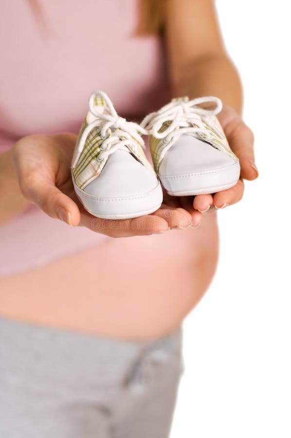 Pregnant woman holding pair of white shoes