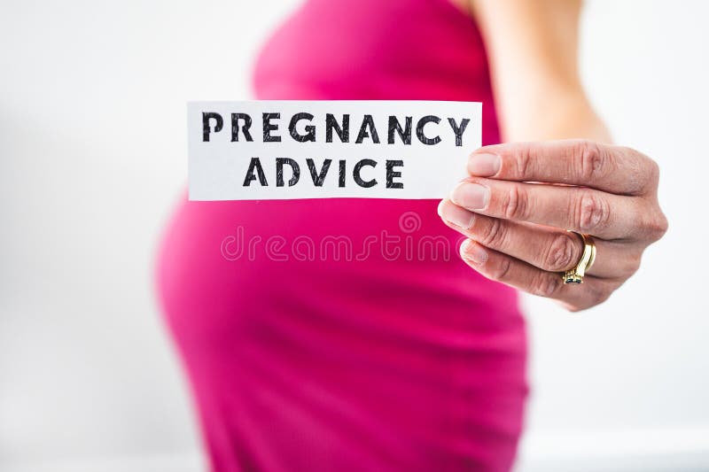Pregnant woman holding Pregnancy Advice sign towards the camera wearing pink dress in the last month of pregnancy stock photos Pregnant woman holding Pregnancy Advice sign towards the camera wearing pink dress in the last month of pregnancy stock photos