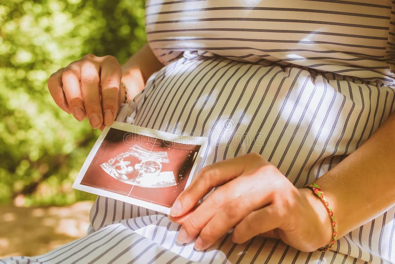 Pregnant woman holding ultrasound sonogram image. Young mother waiting of the baby