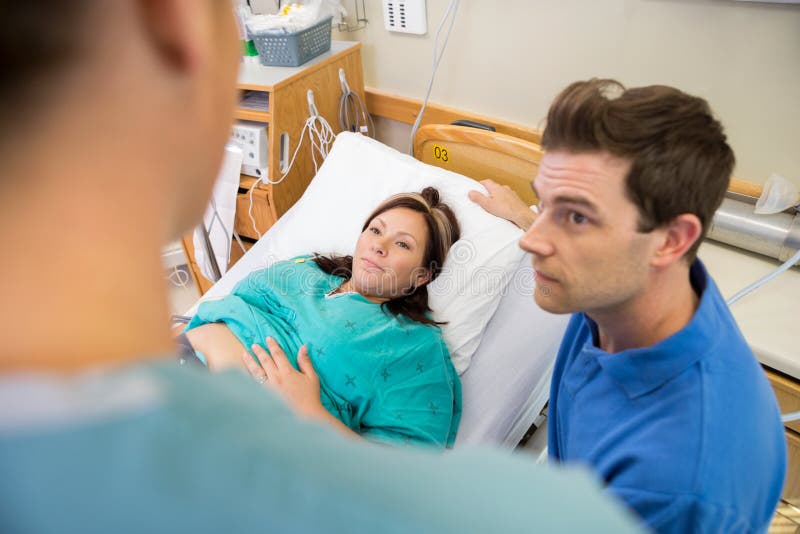 Pregnant Woman And Husband Looking At Nurse In