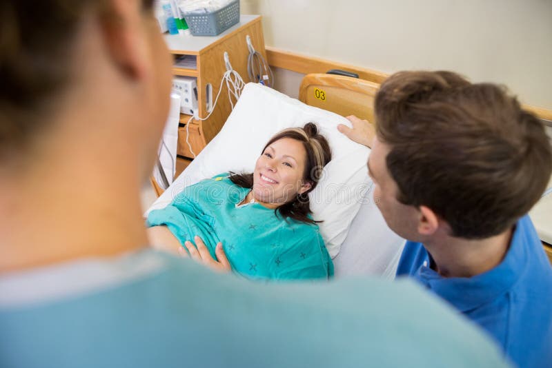 Pregnant Woman Looking At Nurse By Husband In