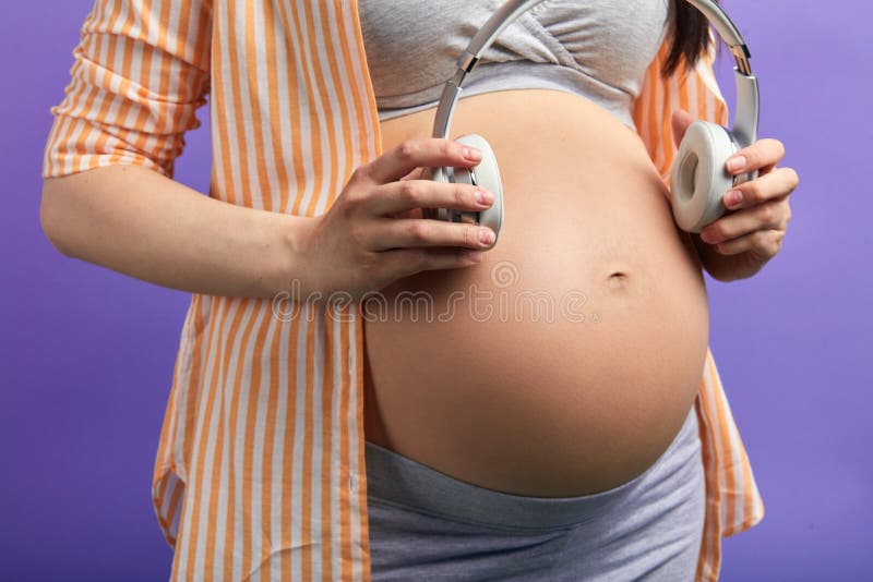 Close Up Of Pregnant Woman Holding Headphones Over Belly, Stock image
