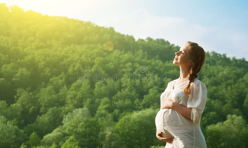 Giovane felice donna incinta rilassarsi e godersi la vita in natura.