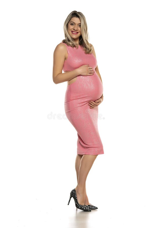 Pregnant woman in tight pink dress posing in studio