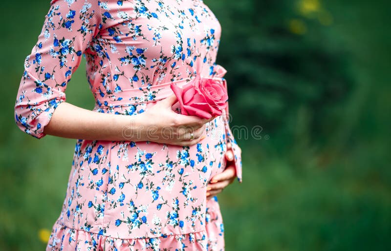 Pregnant woman touching bump whilst holding pink rose girl waiting