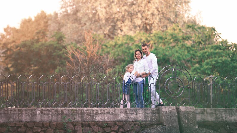 Pregnant woman with her daughter and husband in the park on the bridge royalty free stock image Pregnant woman with her daughter and husband in the park on the bridge royalty free stock image