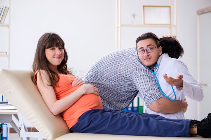 The Pregnant Woman With Her Husband Visiting The Doctor In Clinic Stock