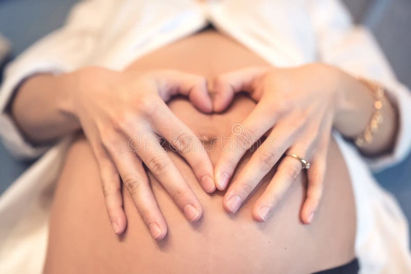 Pregnant young woman holding fingers in a heart shape stock images Pregnant young woman holding fingers in a heart shape stock images