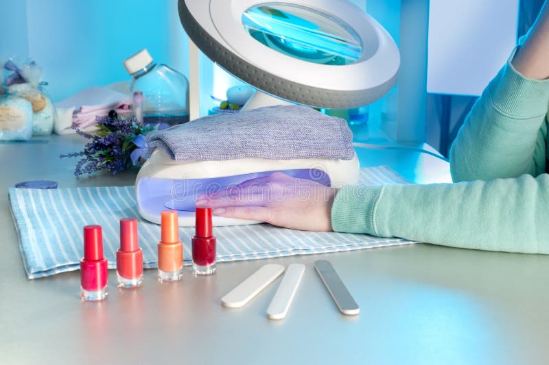 Nail salon, a female hand inside drying UV light machine. Nail salon, a female hand inside drying UV light machine