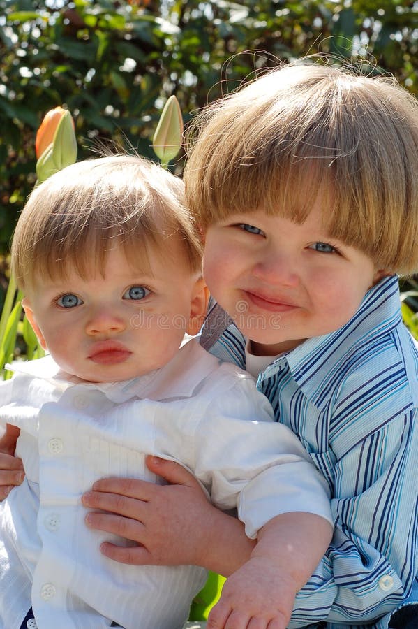 Outdoor vertically framed shot of a young boy holding his baby brother. Outdoor vertically framed shot of a young boy holding his baby brother.