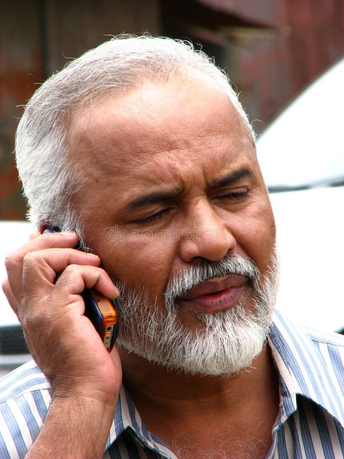 A handsome looking Indian senior businessman worried while talking with someone on the phone. A handsome looking Indian senior businessman worried while talking with someone on the phone