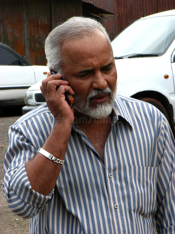 A handsome looking Indian senior businessman worried while talking with someone on the phone. A handsome looking Indian senior businessman worried while talking with someone on the phone