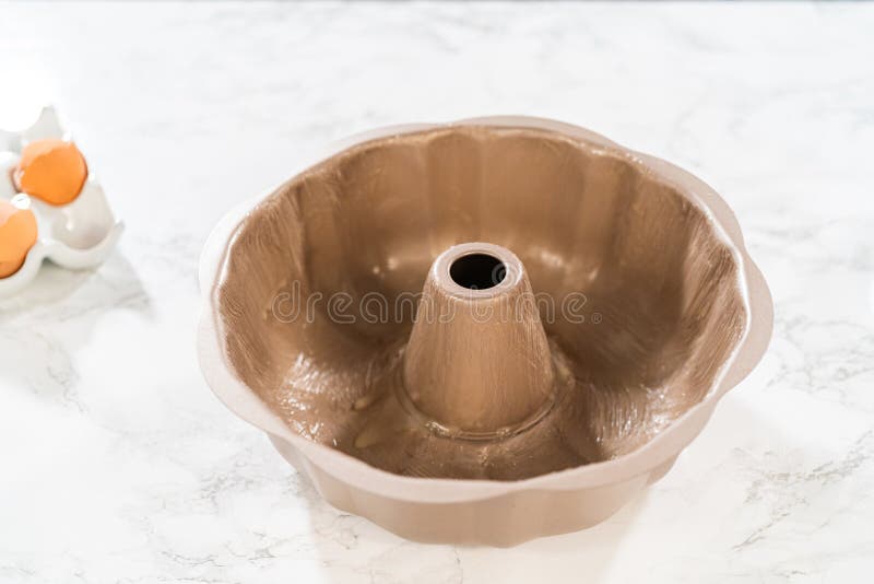 Using a silicone brush, the metal bundt cake pan is greased with melted vegetable shortening, preparing for baking the scrumptious Carrot Bundt Cake. Using a silicone brush, the metal bundt cake pan is greased with melted vegetable shortening, preparing for baking the scrumptious Carrot Bundt Cake.