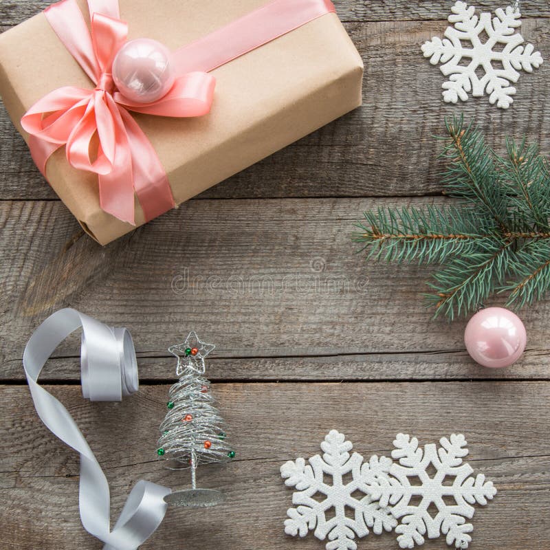 Preparation for Christmas holiday. Christmas gift box with pink ribbon and ball, decor from snowflakes, silver ribbon and decor ar