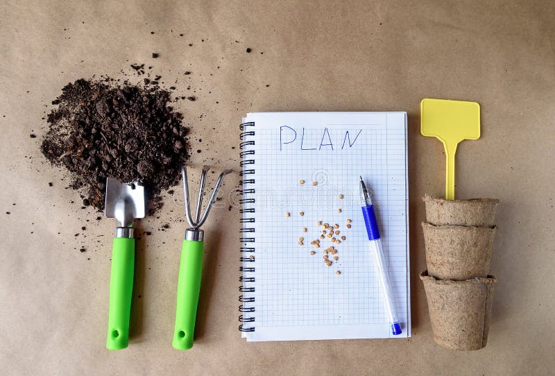 Preparation for planting seeds at home. A notebook with a record of the landing plan. Garden objects on the table top view