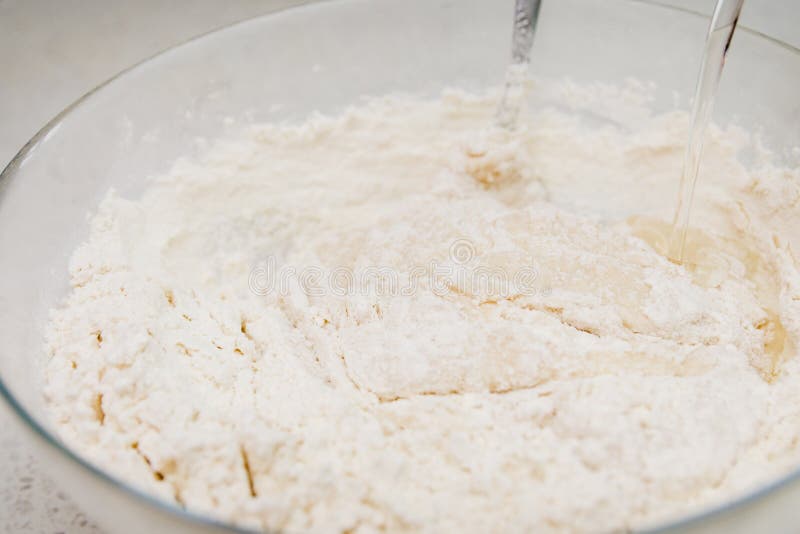 Preparation of the yeast dough. Adding water to the dough in the glass bowl