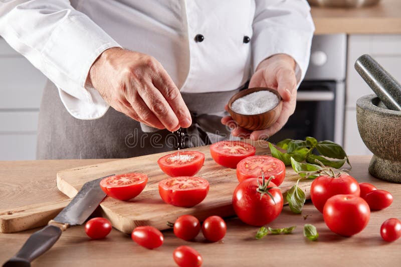 Preparatul vegetal care toarnă sare pe tomate proaspete royalty free stock image