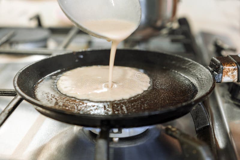 Cooking pancakes. The liquid dough from the ladle is poured onto a round pan. Cooking pancakes. The liquid dough from the ladle is poured onto a round pan