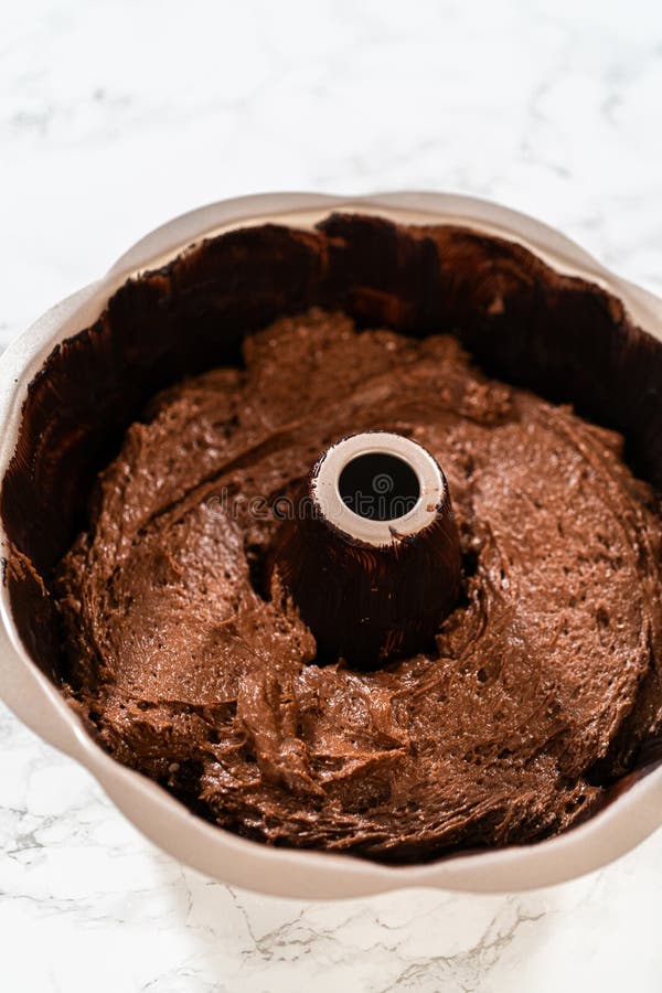 The prepared batter is carefully filled into the greased bundt pan - setting the stage for a delicious Chocolate Bundt Cake. The prepared batter is carefully filled into the greased bundt pan - setting the stage for a delicious Chocolate Bundt Cake.