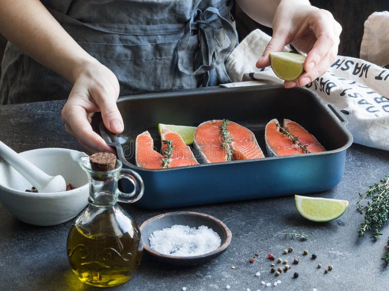 Preparação dos salmões Mãos fêmeas com uma fatia do cal Um potenciômetro com bifes salmon crus imagem de stock royalty free Preparação dos salmões Mãos fêmeas com uma fatia do cal Um potenciômetro com bifes salmon crus imagem de stock royalty free